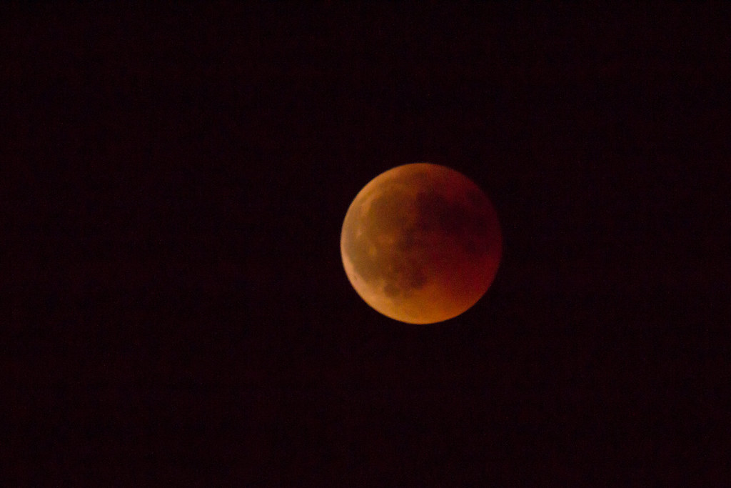 Eclipse lunar total con la luna en color rojo sangre visible en el cielo nocturno, símbolo de liberación y transformación emocional